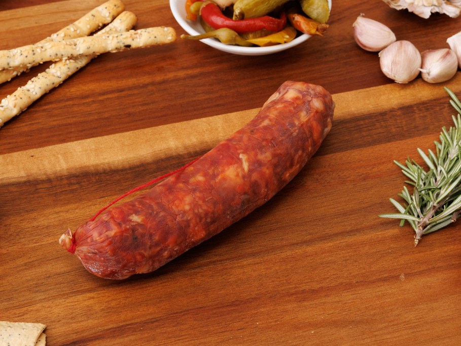 Whole Cacciatore Hot salami tied with red string on a timber board