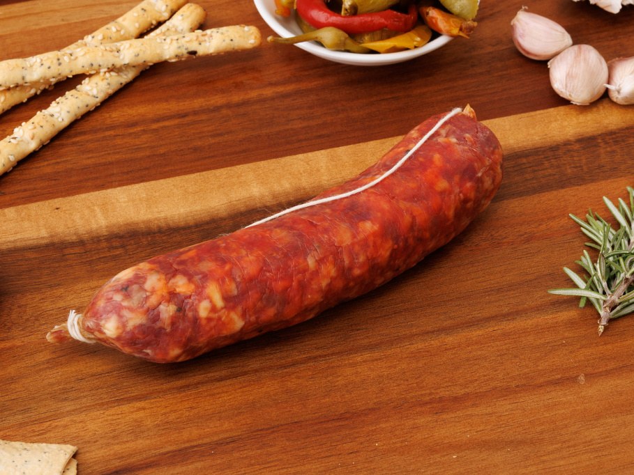 Whole Cacciatore Mild salami tied with white string on a timber board