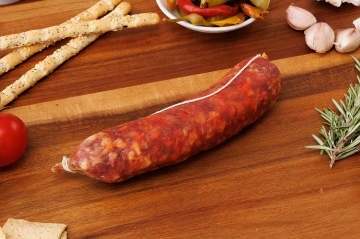 Whole Cacciatore Mild salami tied with white string on a timber board