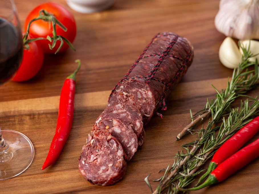 Kangaroo and Red Wine salami sliced on a timber board with red chillies