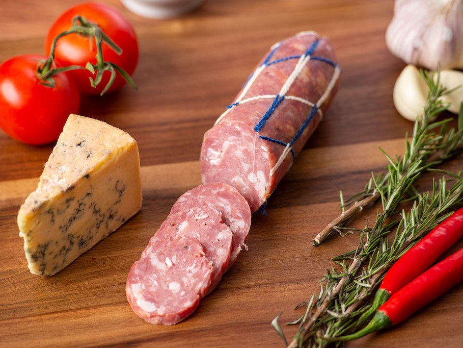 Salami with Blue Vein Cheese sliced on a timber board beside a wedge of blue cheese